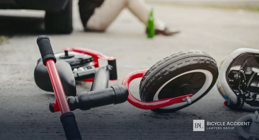 A red child's balance bike and helmet lie on the ground near a blurred person.