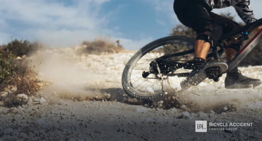A mountain biker kicks up dust and loose rocks while riding fast down a desert trail.