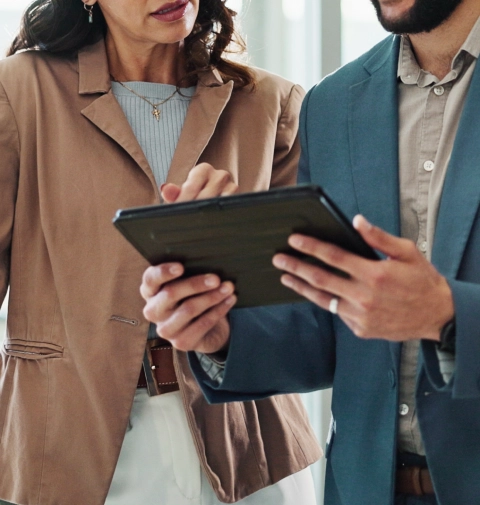 Two professionals reviewing information on a tablet.